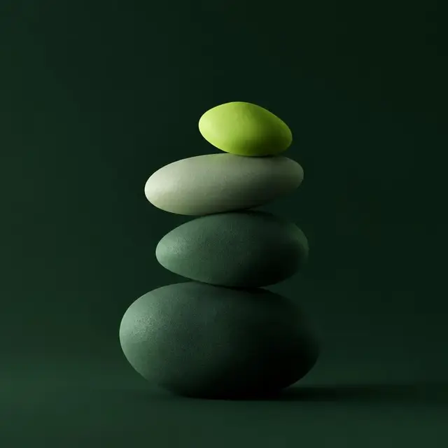 Balanced stack of smooth stones with a lime green stone on top